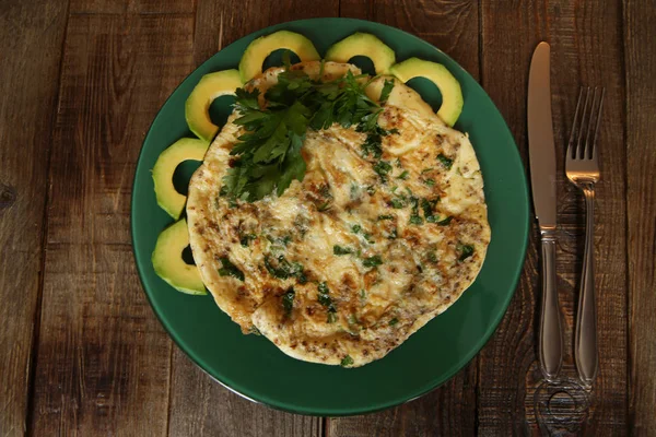 taze maydanoz ve avokado ahşap rustik arka plan üzerinde yeşil bir plaka ile omlet