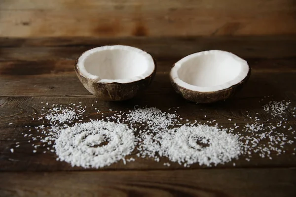 coconut halves with coconut flakes on a wooden background with copy space for text