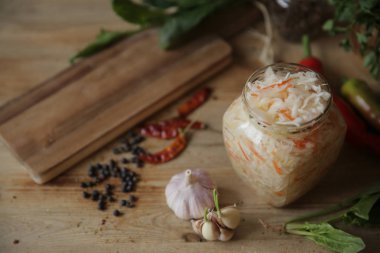 metin için kopya alanı ile baharat ve otlar ile ahşap bir masa üzerinde cam bir kavanozda lahana turşusu