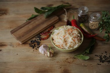  baharat ve otlar ile kopya alanı için metin ile ahşap bir masa üzerinde bir kasede lahana turşusu