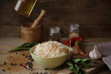 baharat ve otlar ile ahşap bir masa üzerinde bir kasede lahana turşusu