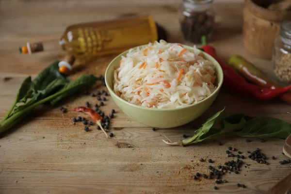 sauerkraut in a bowl on a wooden table with oil in a bottle, spices and herbs