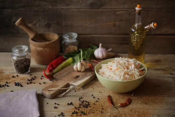 sauerkraut in a bowl on a wooden table with oil in a bottle, spices and herbs