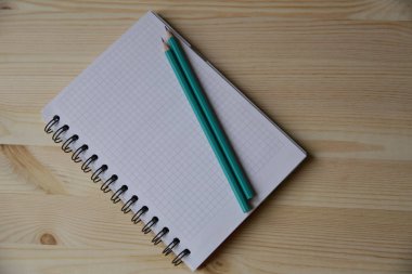 Boş defter ve ahşap masa lambası üzerinde iki kalem