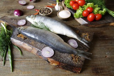 domates ve baharat bir kesme tahtası üzerinde taze ringa balığı