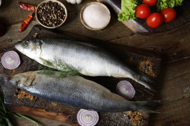 domates ve baharat bir kesme tahtası üzerinde taze ringa balığı