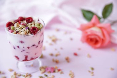 Taze ahududulu yoğurt ve açık pembe arka planda gül. Sağlıklı yiyecekler. Metin için kopyalama alanı ile.