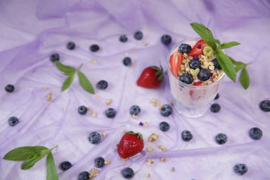 Hafif bir leylak arka plan üzerinde taze yaban mersini ve çilek ile Granola yoğurt parfait. Sağlıklı beslenme kavramı. Metin için kopyalama alanı ile.
