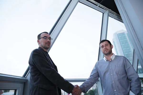 Dos Hombres Negocios Estrechando Mano Frente Una Ventana Panorámica Oficina —  Fotos de Stock