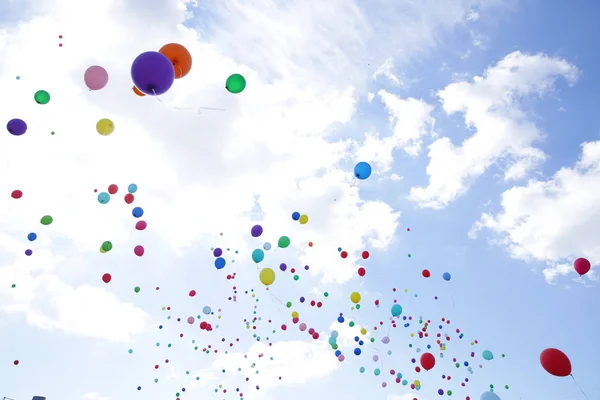 colored balloons fly in the blue sky with white clouds on the holiday