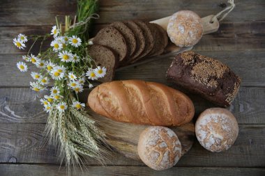 susam ve çörekler ve rustik ahşap arka plan üzerinde kulakları ve çiçekleri ile beyaz ekmek bir somun ile çavdar ekmeği natürmort, üst görünüm, düz yatıyordu