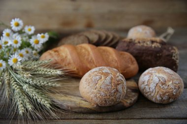 çavdar ve kulaklar ve ahşap rustik arka plan üzerinde papatyalar bir buket ile buğday taze sıcak ekmek, yakın çekim. Metin için kopyalama alanı ile.