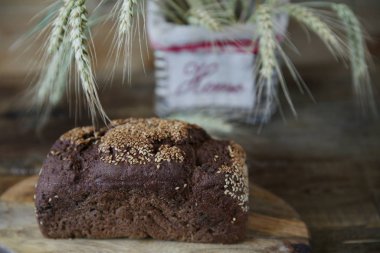 Close. Ahşap rustik arka plan üzerinde yazıt Ev ile bir sepet içinde susam ve çavdar kulakları ile Çavdar ekmeği