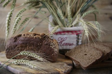 Close. Ahşap rustik arka plan üzerinde yazıt Ev ile bir sepet içinde susam ve çavdar kulakları ile Çavdar ekmeği