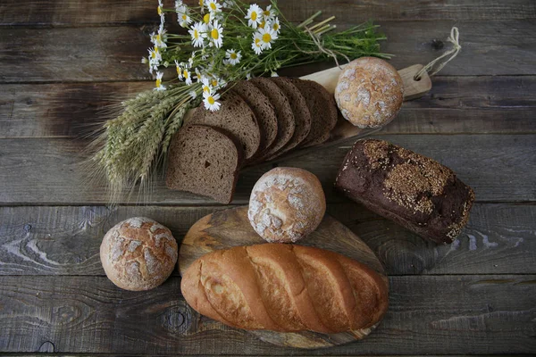 susam ve çörekler ve rustik ahşap arka plan üzerinde kulakları ve çiçekleri ile beyaz ekmek bir somun ile çavdar ekmeği natürmort, üst görünüm, düz yatıyordu
