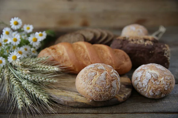 çavdar ve kulaklar ve ahşap rustik arka plan üzerinde papatyalar bir buket ile buğday taze sıcak ekmek, yakın çekim. Metin için kopyalama alanı ile.