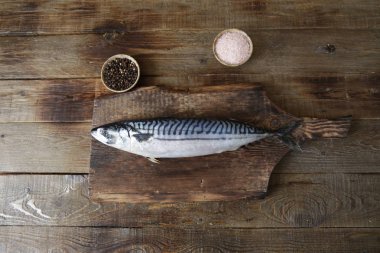 Ahşap kesme tahtası ve metin için kopya alanı ile ahşap rustik arka plan üzerinde tuz ve biber ile taze uskumru. Düz yatıyordu. Üstte görüntü.