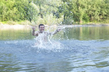 aktif genç mutlu adam berrak bir dağ nehri veya göl suyunda bir sıçrama yapar
