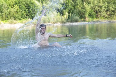 aktif genç mutlu adam berrak bir dağ nehri veya göl suyunda bir sıçrama yapar