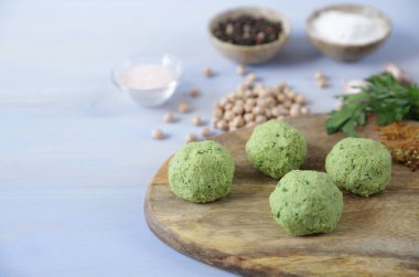 Hazırmalzemeler ile hafif ahşap bir arka plan üzerinde ahşap bir kesme tahtası üzerinde nohut, otlar ve baharattaze ham falafel topları. Vegan taco. Vejetaryen sağlıklı yemek. Metin için kopyalama alanı ile.