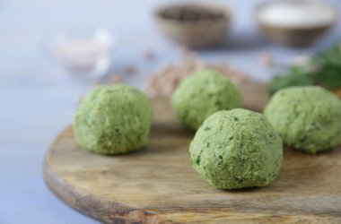 Hazırmalzemeler ile hafif ahşap bir arka plan üzerinde ahşap bir kesme tahtası üzerinde nohut, otlar ve baharattaze ham falafel topları. Vegan taco. Vejetaryen sağlıklı yemek. Close.