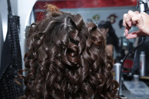 年轻的黑发女人在美发沙龙长头发 理发师使黑发 卷发的发型 理发店和理发店的概念 — 图库照片