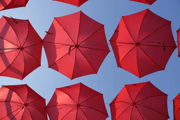 Many red umbrellas against the blue sky. View from below. Abstract background with red umbrellas. Seamless pattern with umbrellas.