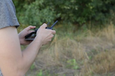 adam elleri drone quadcopter kontrol panelini tutun. Adam alan üzerindeki drone uçuşunu kontrol ediyor. Tarımda yeni teknolojiler. Yüz olmadan.