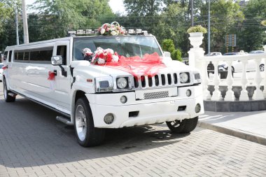 beyaz düğün limuzin kırmızı şeritler, düğün halkaları ve çiçekler ile dekore edilmiştir. Düğün konsepti.