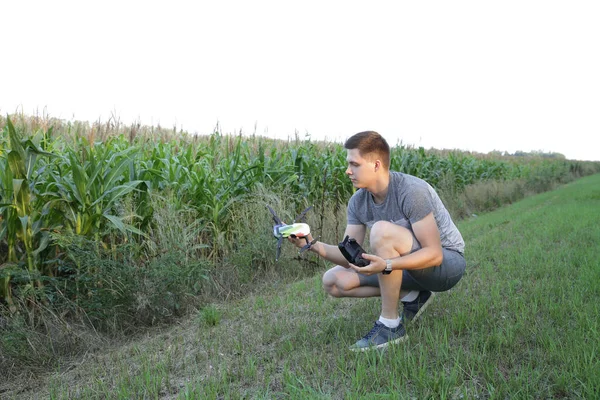 활동적인 청년은 드론을 사용하여 옥수수밭 날아다닌다 리모컨으로 항공기를 제어합니다 농업의 — 스톡 사진