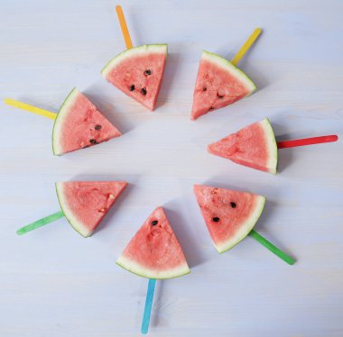 beyaz mavi bir arka plan üzerinde bir daire içinde ortaya koyulan renkli çubukları ile taze olgun kırmızı karpuz dilimleri. Organik sağlıklı yiyecekler. Diyet, detoks.