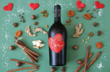  Düz yatıyordu. Mulled şarap Noel Sevgililer Günü Love için baharat ve kurutulmuş meyve ile yeşil bir arka plan üzerinde aşk hakkında bir yazıt ile bir şişe üzerinde kırmızı bir kalp ile şarap bir şişe ile Natürmort. Kartpostal, desen.