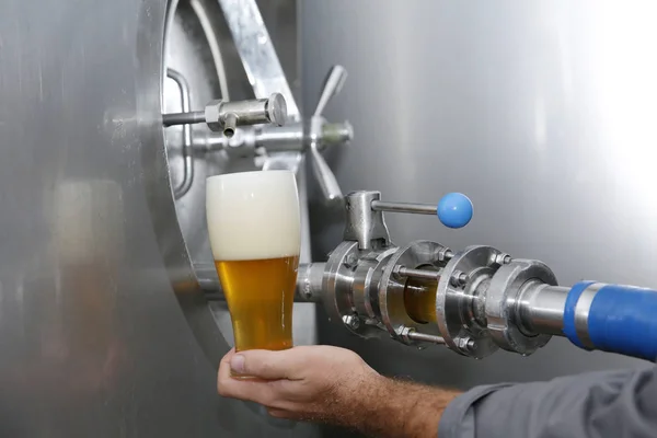 タンクの背景にテイスティングタンクから手にビールのフルグラス 金属タンク アルコール飲料の製造 醸造所のクラフト醸造装置 — ストック写真