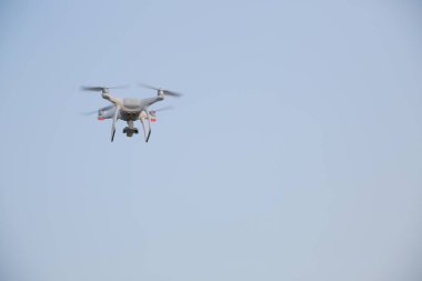 Beyaz insansız hava aracı, quadrcopter mavi gökyüzüne karşı uçuyor. Metin için kopyalama alanı ile. Hava fotoğrafçılığı ve video çekimi için ekipmanlar. Yeni teknolojiler ve yenilikler kavramı.