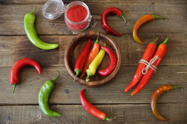 organik kırmızı, ahşap bir tabak ve ahşap rustik bir masa üzerinde karabiber üzerinde yeşil acı biber. Düz yatıyordu. Üst te. Doğal baharat veya baharat. Poster, desen, arka plan, doku.