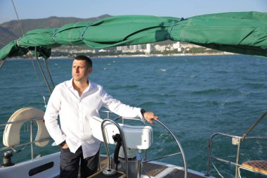 beyaz çekici adam denizde bir yat dümen duruyor. Yelken, turizm, seyahat ve insan kavramı. Direksiyon ve navigasyon üzerinde Mutlu adam.