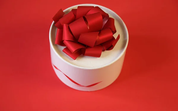 white gift box with red big bow isolated on a red background. Christmas, Valentine's Day, Birthday other holidays. With copy space for text. Top view. Poster, Pattern, background, card.