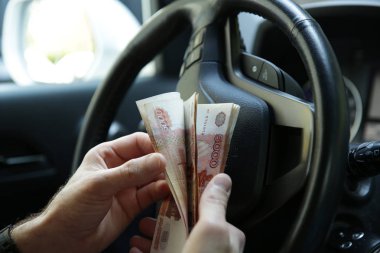 Parayla el sıkışmak. Banknotlar bir arabanın direksiyonunda elinde beş bin Rus rublesi. Nakit kağıt para. Beş bininci fatura. Otomobil endüstrisi