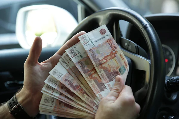 Hand with money. Banknotes five thousand Russian rubles in the hand on the steering wheel of a car. Cash paper money. Five thousandth bill. Auto industry
