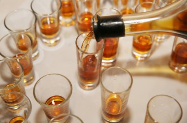 Barmen ya da barmen eski konyağı küçük bardağa doldurur. Masada eski bir şişe konyak ve bir sürü küçük bardak var..