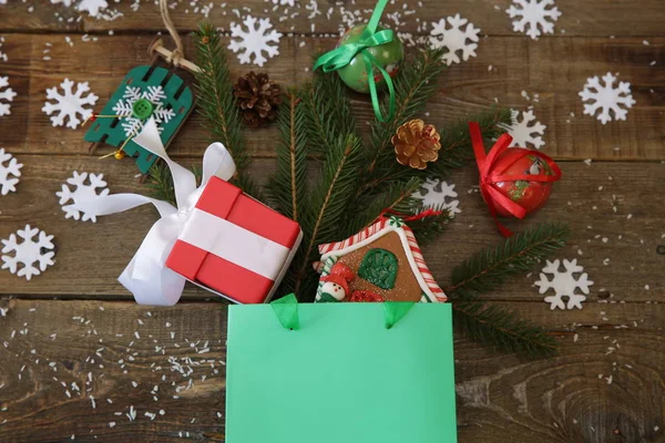 Weihnachtsbaumzweig Mit Geschenken Lebkuchen Dekorationen Einer Grünen Papiertüte Und Schneeflocken — Stockfoto