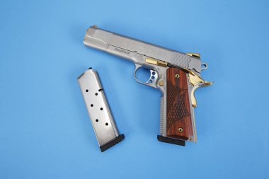 Ahşap, altın ve mavi arka planda kurşun tutacağı olan tabanca ya da tabanca. Silah konsepti. Koruma ve şiddet.