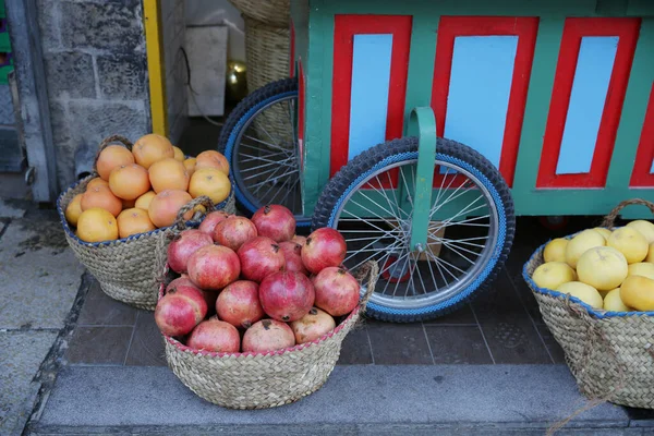 トレーラーホイールを背景に通りに大きなバスケットにザクロの果物や柑橘類のオレンジやグレープフルーツ ストリート トレーディングのコンセプト — ストック写真