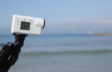 Deniz arka planındaki blogcu için dijital aksiyon kamerası. Beyaz renk. Yakın plan..