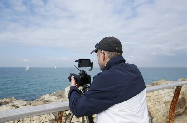 photographer or videographer or blogger with digital camera in action on a sea