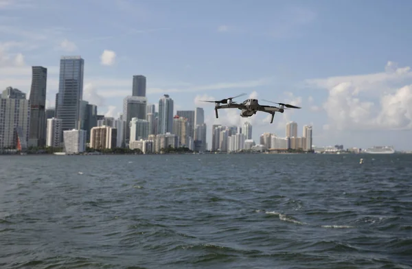 drone or quadcopter in flight against the background of city skyscrapers and water of the sea or river. New technology concept. Panorama of the city.