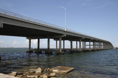 Nehir ya da deniz üzerinde büyük bir köprü. Yolda fener ışığı var.