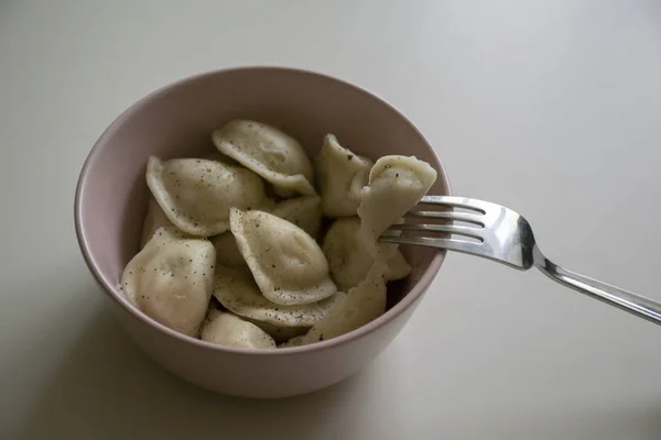 Gümüş çatal ile beyaz tabloda pembe plaka onlara biber ile sıcak köfte