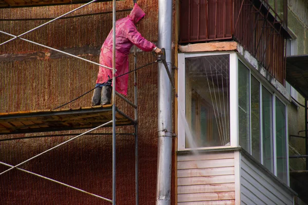 Novosibirsk, Akademgorodok 8 Eylül 2018: bir iskele üzerinde pembe bir yağmurluk işçi yıkar bir balkon