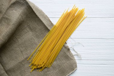 Beyaz ahşap zemin üzerinde çuval bezi üzerinde spagetti. Üstten görünüm